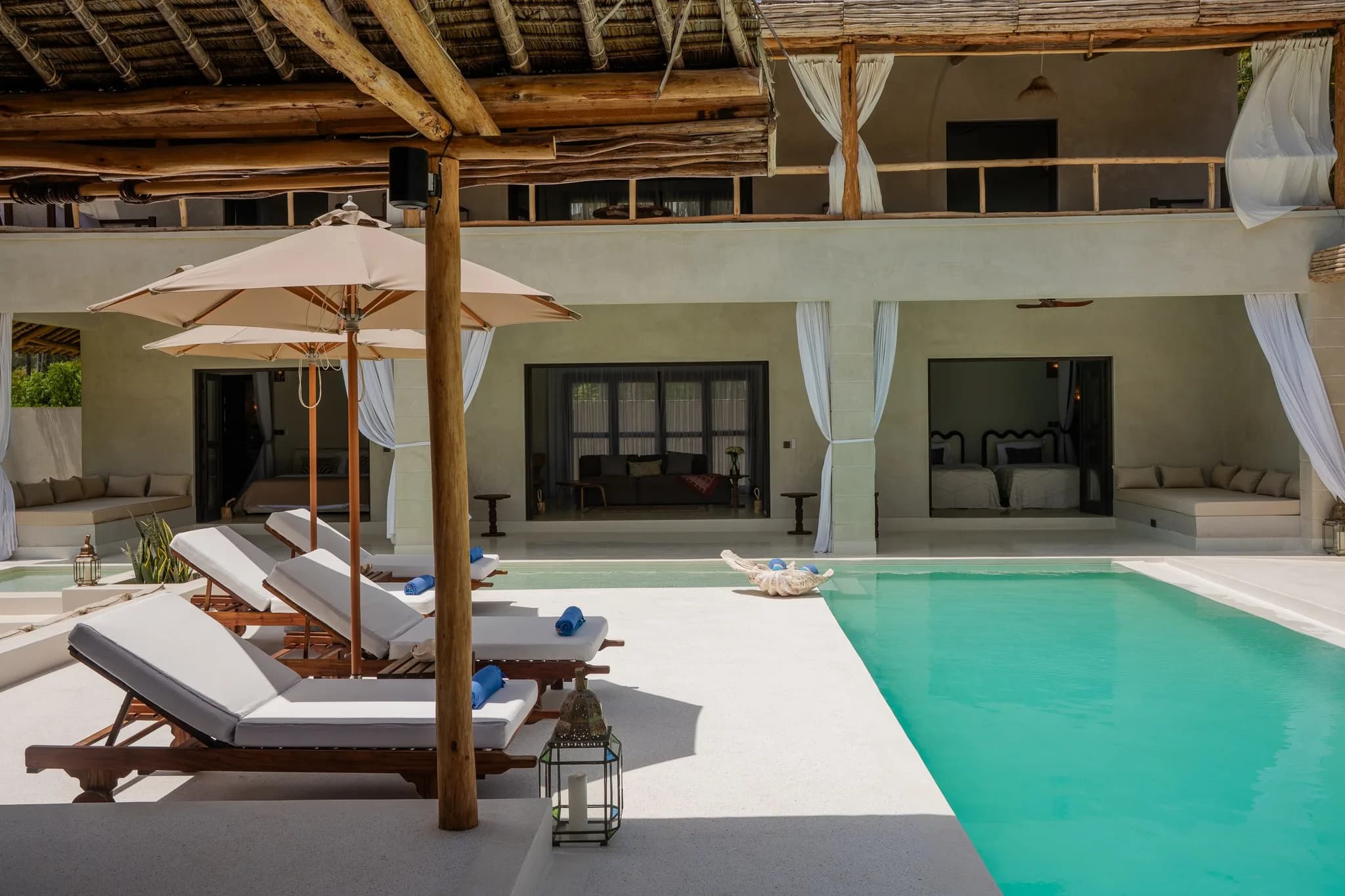 Bedroom interior with king bed, neutral linens, and pool view