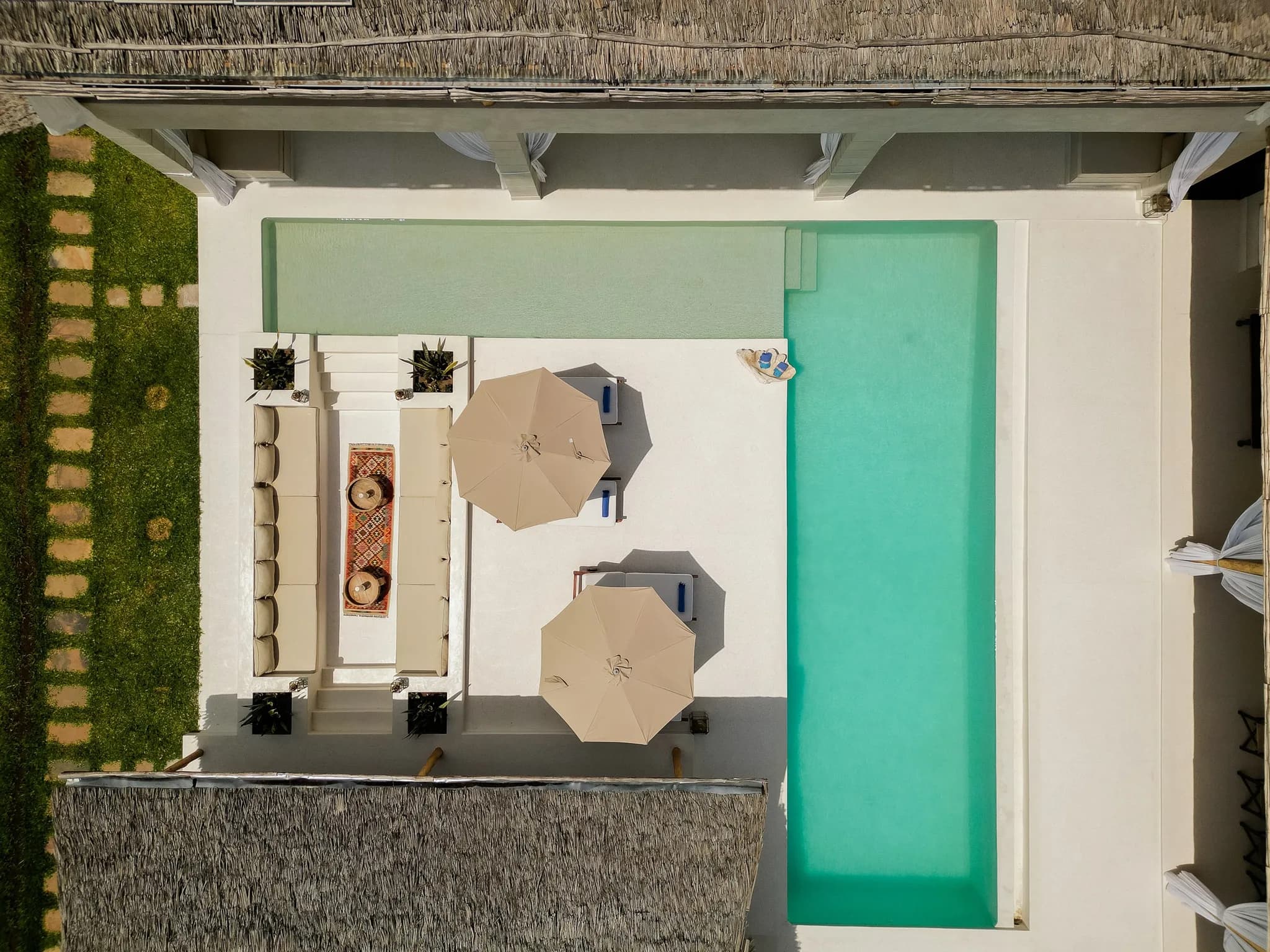Overhead view of modern villa infinity pool area with loungers and umbrellas