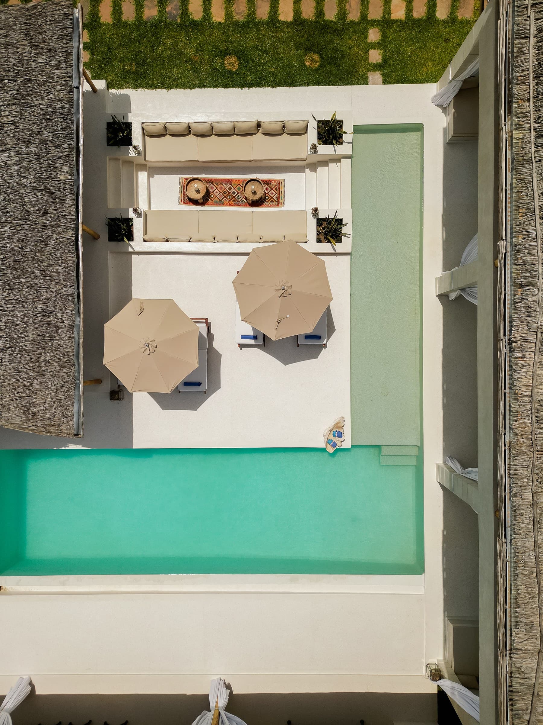 Bedroom with open doors revealing pool, daybed, and tropical plants