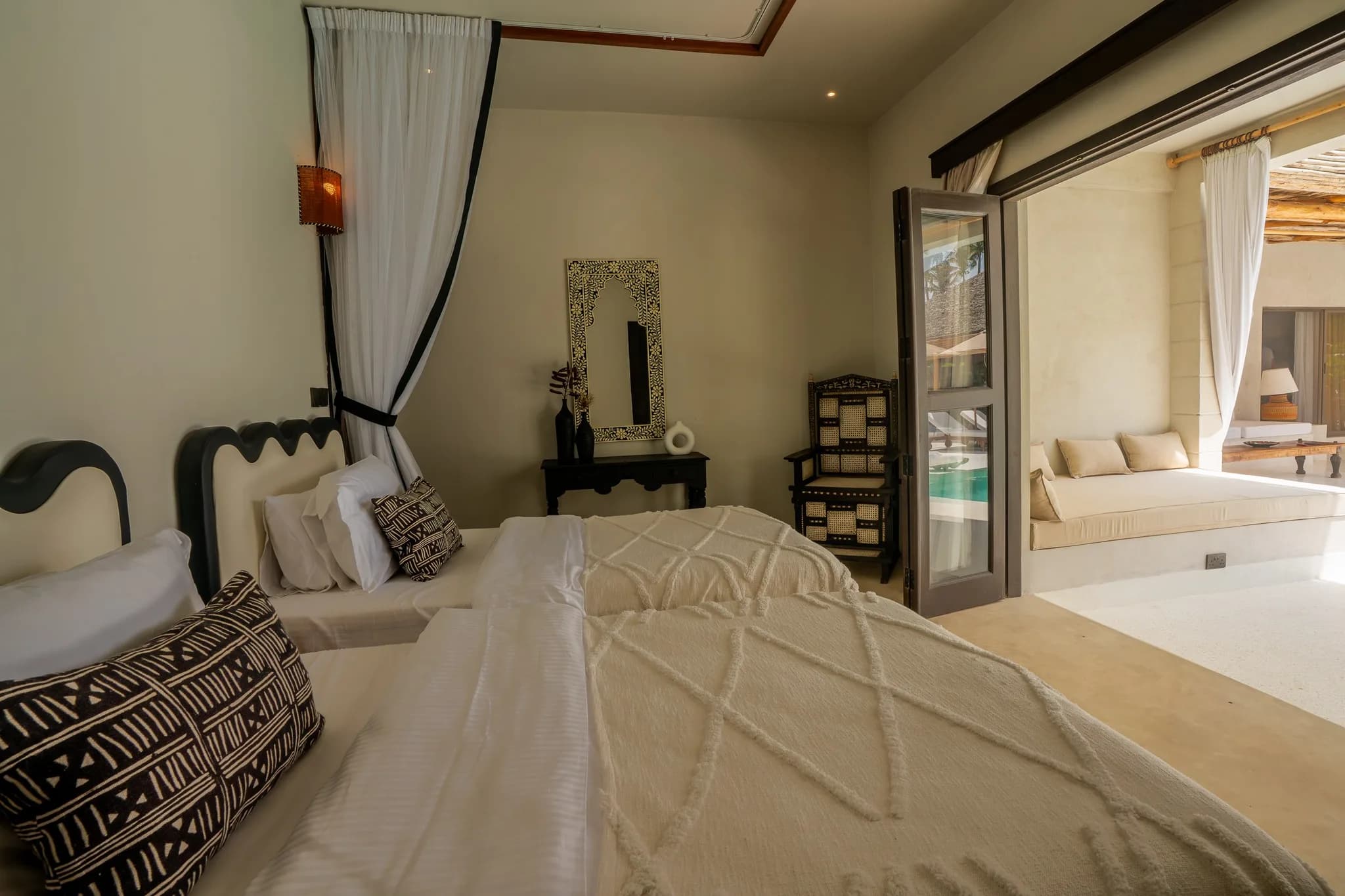 Luxurious twin beds with white bedding and open doors to pool