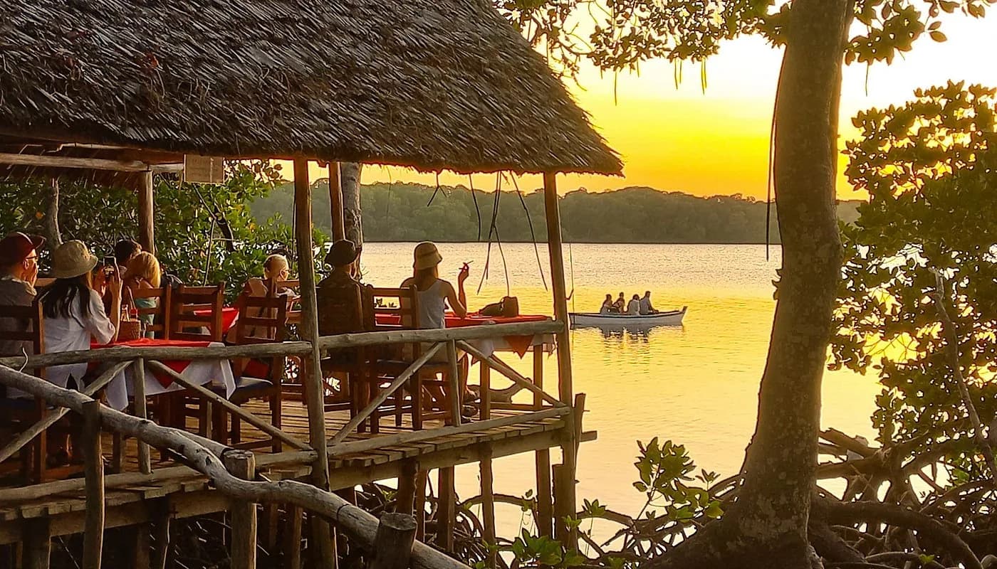 Waterfront restaurant on wooden deck overlooking lake with mangroves at sunset